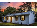 Evening view of a renovated brick home highlighting its new windows, shutters, and inviting entrance at 463 E Main Street, Harleyville, SC 29448