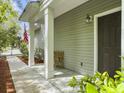 Inviting front porch with classic columns, wooden bench, and American flag displayed at 8810 Gilston Ln, North Charleston, SC 29420