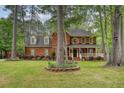 Beautiful two-story brick home with a inviting front porch, surrounded by mature trees and landscaped gardens at 104 Leighton Ct, Summerville, SC 29485