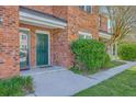 Up-close view of a brick townhome with a green front door and manicured landscaping at 1421 Dove Run Dr # C, Charleston, SC 29412