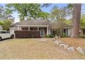 Inviting single-story home with a brick facade, covered porch, and lush greenery in a tranquil setting at 181 Commons Way, Goose Creek, SC 29445