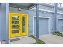 Close-up of a townhome entrance with a bright yellow door, gray siding, and a single-car garage at 1816 Orangeburg St, North Charleston, SC 29405