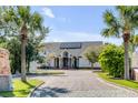 Elegant home with solar panels, framed by palm trees and a long brick driveway at 1954 Sandy Point Ln, Mount Pleasant, SC 29466