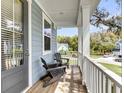 Relaxing covered porch features chairs, wooden floors, and a view of the neighborhood at 2568 Hatch Dr, Johns Island, SC 29455
