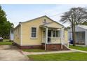 Charming yellow home featuring a cozy front porch with white railing and brick foundation at 3728 Tim St, North Charleston, SC 29405