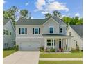 Charming two-story home with a covered front porch, a two-car garage, and manicured lawn at 86 Red Bluff St, Summerville, SC 29483