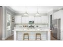 Bright kitchen boasts white cabinetry, an island with seating, and stainless steel appliances at 130 Maritime Way, Summerville, SC 29485