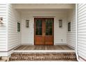 Inviting front porch with double wooden doors, brick steps, white siding and sconce lighting for a warm welcome at 1412 Jackson St, Mount Pleasant, SC 29464