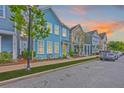 Street view showcases colorful homes with mature trees and well-manicured lawns at sunset at 1656 Indy Dr, North Charleston, SC 29405