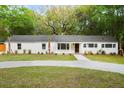 Lovely home showcasing its white exterior, neatly landscaped front yard and mature trees at 920 Julia St, Charleston, SC 29412