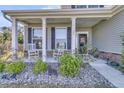 Inviting front porch with white columns, rocking chairs, and stone accents, offering a cozy welcome at 106 Lakelyn Rd, Moncks Corner, SC 29461