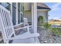 Close-up of the front porch featuring classic white rocking chairs, stone detailing, and manicured landscaping at 106 Lakelyn Rd, Moncks Corner, SC 29461