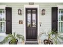 Elegant front door with black trim, decorative lights, and potted plants at 1063 Hills Plantation Dr, Charleston, SC 29412