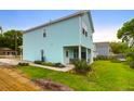 View of the rear of the two-story light blue home with a covered porch and lawn at 1130 5Th Ave, Charleston, SC 29407