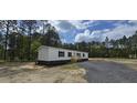 Beautiful single-story home with white siding and a brick foundation; a gravel driveway leads to a wooden fence at 115 Sandy Oaks Ln, Cross, SC 29436