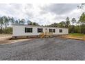 Charming single-story home with white siding and black shutters; a gravel driveway leads to the property at 115 Sandy Oaks Ln, Cross, SC 29436