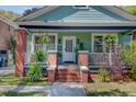 Close-up of charming craftsman porch with brick pillars and vibrant plants at 1157 King St, Charleston, SC 29403