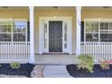 Close-up of a charming front porch with decorative columns, a black front door, and manicured landscaping, creating a welcoming entry at 150 Sugar Magnolia Way, Charleston, SC 29414