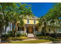 Inviting yellow two-story home featuring a cozy front porch, manicured lawn, and beautiful palm trees at 1700 Paradise Lake Dr, Mount Pleasant, SC 29464