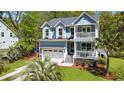 Home exterior showcasing a two-car garage, double porches, well-maintained lawn, and mature palm tree at 2111 Nicholas David Path, Johns Island, SC 29455