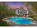 Backyard view featuring the home, in-ground pool, lounge chairs, and a well-manicured lawn surrounded by lush trees at 2111 Nicholas David Path, Johns Island, SC 29455