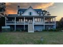 Beautiful two-story home with wraparound porch and staircase, set against a colorful sunset sky at 2312 Rushland Landing Rd, Johns Island, SC 29455