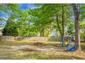 Large grassy backyard with mature trees providing shade, featuring a wooden fence and a swing set at 301 Huntington Ct, Hanahan, SC 29410