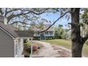Charming two-story home featuring a picturesque wrap-around porch and a long, winding driveway through a lush, landscaped yard at 4584 Olde Smoak House Rd, Meggett, SC 29449