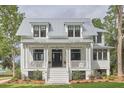 Inviting two-story home boasts a metal roof, white exterior, and welcoming front porch with stylish columns at 791 Hughes Rd, Johns Island, SC 29455