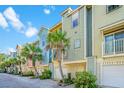 Colorful townhome exterior featuring private garages, and lush tropical landscaping with palm trees at 1011 Lighterman Way, Charleston, SC 29412