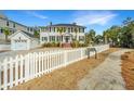 Two-story home with white picket fence, detached garage, professional landscaping, and ample curb appeal at 1075 Avenue Of Oaks, Charleston, SC 29407