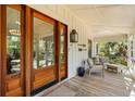 Inviting front porch with seating, wooden floors, and a beautifully crafted wooden front door at 1316 Thompson, Sullivans Island, SC 29482