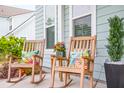 Close-up of a charming front porch with wooden rocking chairs, decorative pillows, and colorful flower arrangements at 144 Sandy Bend Ln, Summerville, SC 29486