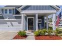 Welcoming front porch with white columns, rocking chairs, and neatly trimmed landscaping at 202 Morning Song St, Summerville, SC 29485