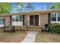 Close up of double front doors with a cozy bench and blossoming shrubbery on the porch at 223 Dandridge Rd, Walterboro, SC 29488