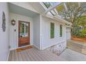 Charming home exterior showcasing a wood front door, covered porch, and manicured landscaping at 26 Edgewater Aly, Isle of Palms, SC 29451