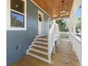 Inviting porch with a wood ceiling, a modern light fixture, white railings, and wooden steps at 3683 Hilton Dr, Johns Island, SC 29455