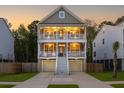 Charming two-story home features a double porch lit at sunset, with a well-manicured lawn at 3718 Sandy Gate Ln, Mount Pleasant, SC 29466