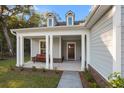 Inviting covered front porch with stately columns, bench seating and view of the wooden entry door at 4263 Hugh Bennett Dr, Johns Island, SC 29455