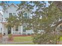 Charming two-story home with a well-manicured lawn and inviting front porch, nestled under lush trees at 1032 Avenue Of Oaks, Charleston, SC 29407