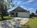 Welcoming one-story home with a two-car garage and a lush green lawn at 1119 Moss Grove Dr, Moncks Corner, SC 29461