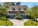 Charming two-story home boasts a welcoming front porch, well-manicured lawn, and a circular driveway leading to a two-car garage at 1339 River Otter Court, Mount Pleasant, SC 29466