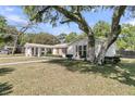 A wide view of the one-story home with a lush tree in the front yard at 1387 W Lenevar Dr, Charleston, SC 29407