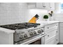 Close-up of a kitchen with a stainless steel gas range, white cabinetry, and quartz countertops at 139 Tradd St # 2, Charleston, SC 29401