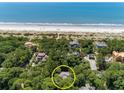 Aerial view of the home's location surrounded by mature trees near a white sand beach at 14 Royal Beach Dr, Kiawah Island, SC 29455