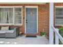 Close up of blue front door and seating on the charming, brick front porch at 237 Cypress Dr, Walterboro, SC 29488