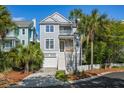 Inviting two-story home featuring a garage, front porch, well-manicured lawn, and lush landscaping at 40 Grand Pavilion Blvd, Isle of Palms, SC 29451