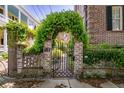 Wrought-iron gate framed by brick pillars covered in vines and foliage at 55 Laurens St # 55-A, Charleston, SC 29401