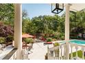 Covered porch view of the backyard oasis featuring a pool, outdoor lounge, and lush greenery at 5680 Dixie Plantation Rd, Hollywood, SC 29449