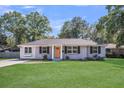 Charming brick home with a lush green lawn and inviting front porch with an orange colored front door at 733 Longfellow Rd, Charleston, SC 29407